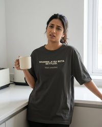 Indian woman standing in kitchen holding a coffee mug 
wearing Sharma Ji Ka Beta Settled Main Unsettled oversized 
washed black tee — lifestyle shot | Aavitra